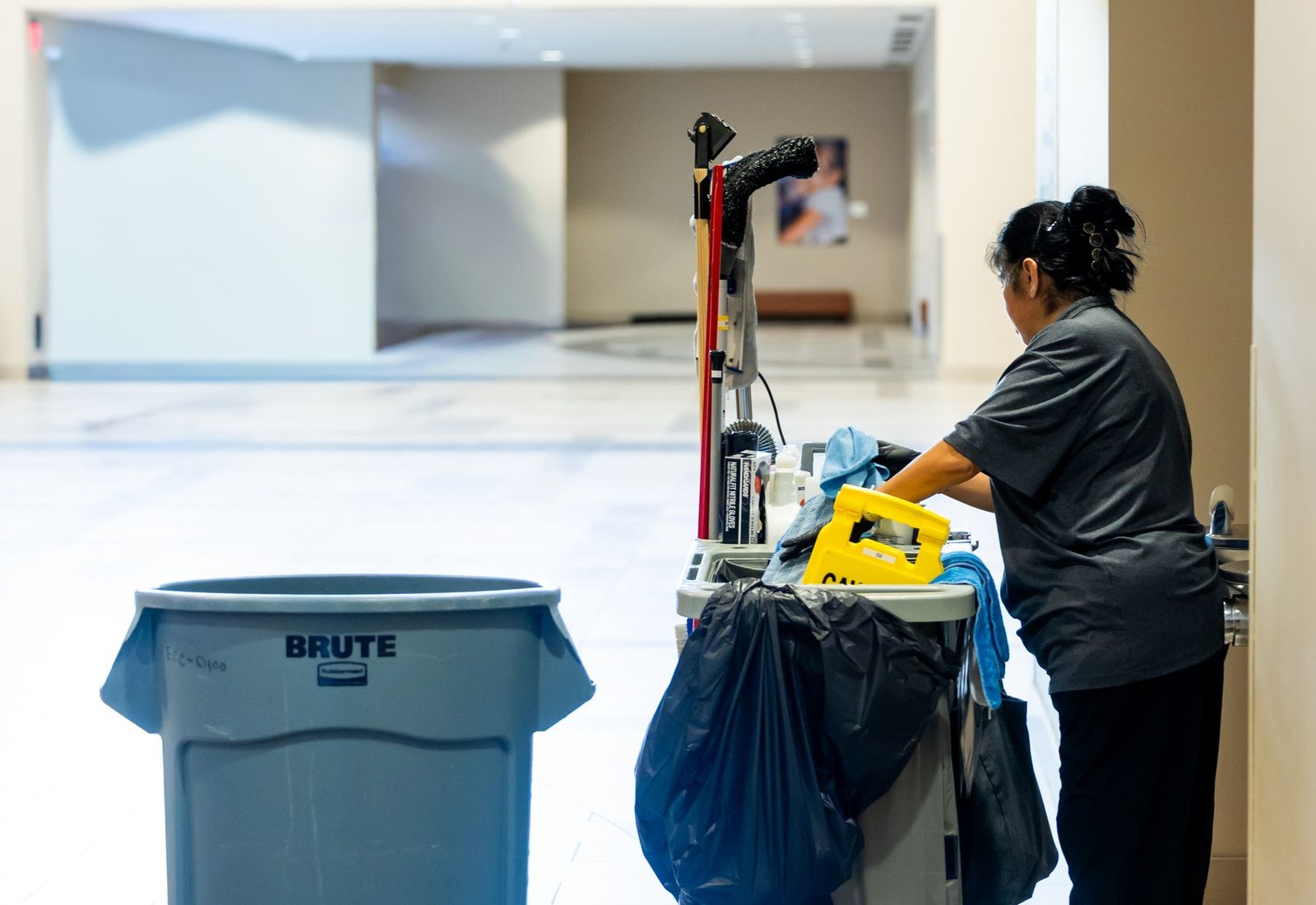 Janitorial professional working with a cleaning cart in a commercial hallway