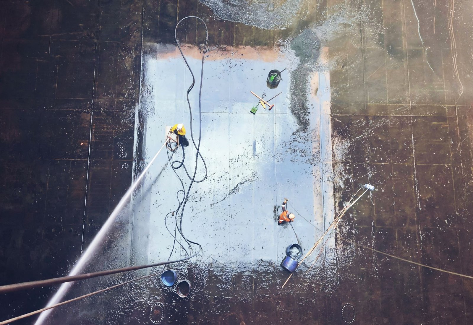 Workers using professional pressure equipment to clean a large commercial floor